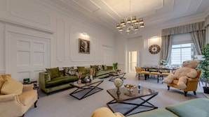 Un salon spacieux avec un canapé vert, un grand fauteuil et un coin repas à l’arrière-plan.