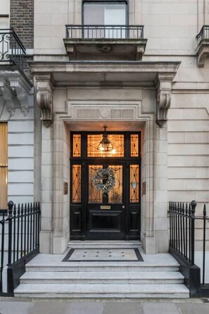 A building entrance with a black door, a wreath, and a light fixture above the door. - Spacious Elegance on Harley Street - 3 Bed Apartment (London)