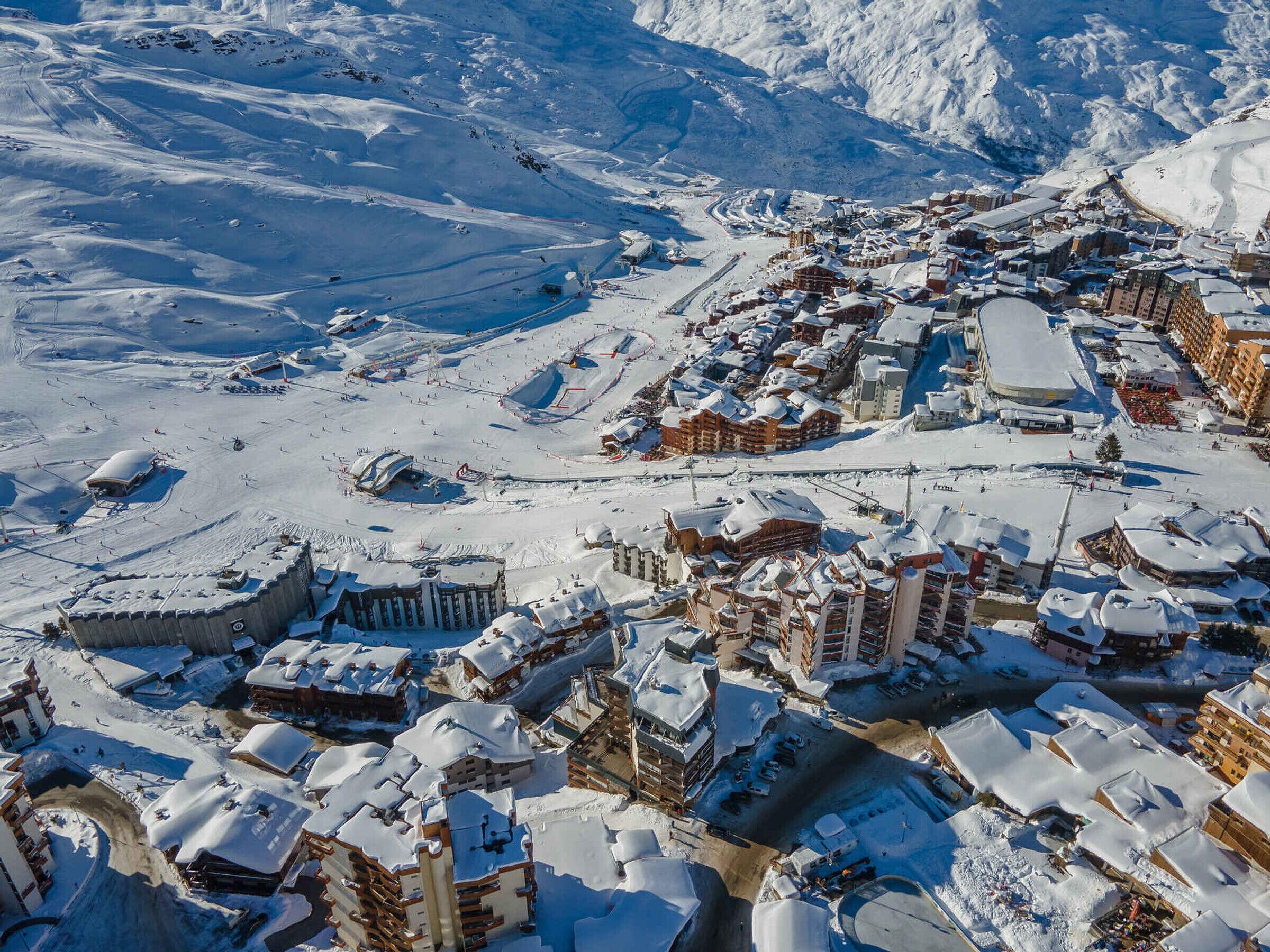 Une ville de montagne enneigée, avec des bâtiments traditionnels en bois et une station de ski.