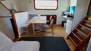 Un intérieur de camping-car compact comprenant un coin cuisine, un espace repas, une petite salle de bain et un espace nuit.
