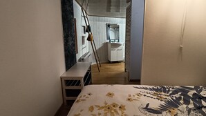 Une chambre à coucher avec un lit, une table de chevet, une commode et une salle de bain visible à travers une porte ouverte.