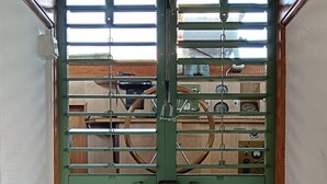 Une porte verte avec une fenêtre, un plafond en bois et un panneau de commande visible, équipé de divers indicateurs.