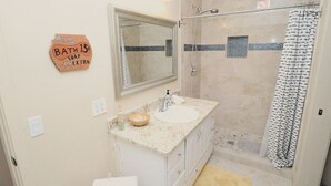 Ein Badezimmer mit Waschbecken, Spiegel, Dusche und Handtuchhalter.
