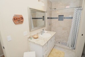 Une salle de bain équipée d’un lavabo, d’un miroir, d’une douche et d’un porte-serviettes.
