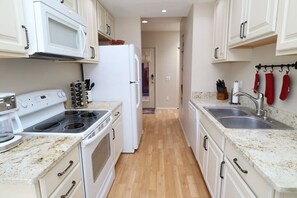 A kitchen with white cabinets, a microwave, a stove, and a refrigerator.