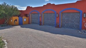 Ein Gebäude mit drei Garagenöffnungen, einer Schotterauffahrt und einem kleinen Baum.