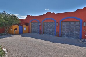 Un bâtiment avec trois portes de garage, une allée gravillonnée et un petit arbre.