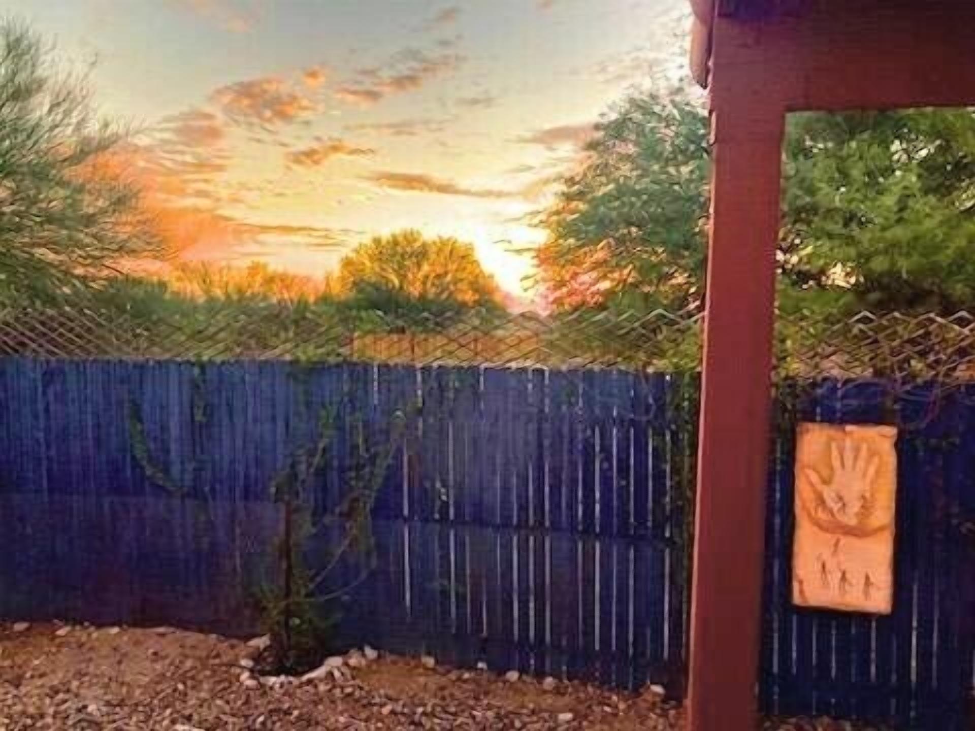 Un patio trasero cercado con un poste de madera y un letrero pintado a mano.