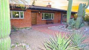 A single-story brick house with a patio, surrounded by cacti and agave plants. - The Duke - Iconic Foothills Escape with Pool &Spa (Tucson)