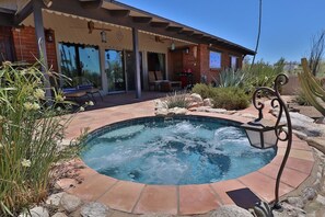 A hot tub surrounded by a patio area with a brick house in the background. - The Duke - Iconic Foothills Escape with Pool &Spa (Tucson)
