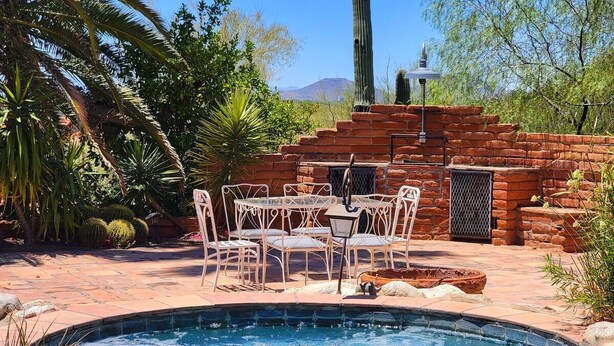 A swimming pool with a brick patio, surrounded by white chairs and a table. - The Duke - Iconic Foothills Escape with Pool &Spa (Tucson)