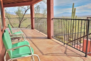 A covered outdoor seating area with chairs and a view of cacti and mountains. - Desert Paradise at Trails End (Tucson)