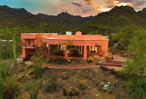 A modern two-story house with a balcony, surrounded by desert vegetation and mountains in the background. - Desert Paradise at Trails End (Tucson)