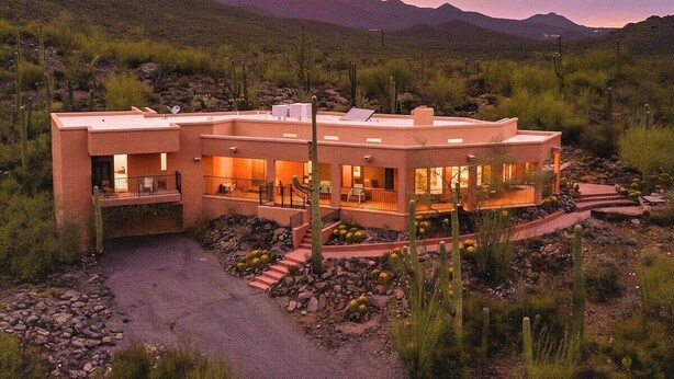 A modern house with a flat roof, multiple balconies, and a paved driveway. - Desert Paradise at Trails End (Tucson)