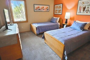 A bedroom with two beds, a desk with a computer, and a window with a view of trees. - Desert Paradise at Trails End (Tucson)
