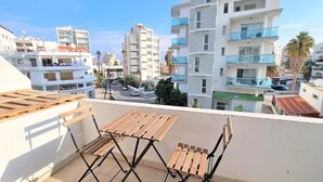 Ein Balkon mit Holzmöbeln und Blick auf moderne Gebäude.