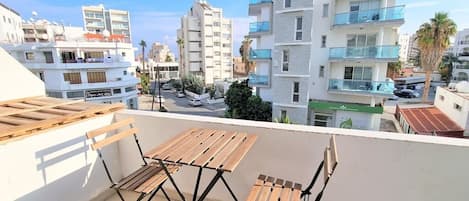 Un balcón con mobiliario de madera y vistas a edificios modernos.
