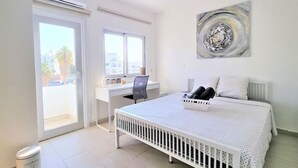 Ein Schlafzimmer mit Bett, Schreibtisch und Fenster.