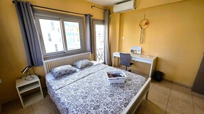 Un dormitorio con cama, escritorio, silla, radiador y aire acondicionado.