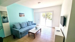 Ein Wohnzimmer mit einem blauen Sofa, einem Holztisch und einem Fernseher auf einem Schrank.