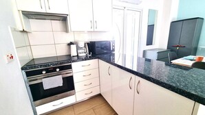 Eine moderne Küche mit weißen Schränken, einer schwarzen Arbeitsplatte, einer Mikrowelle und einer Kaffeemaschine.