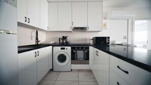 A modern kitchen with white cabinets, a washing machine, a microwave, and a coffee maker. - Cozy Sea View Apt w/ pool access + Netflix (Larnaka)