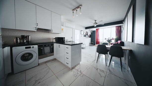 Une cuisine moderne équipée d’un lave-linge, d’un four et d’un coin repas avec des chaises et une table.