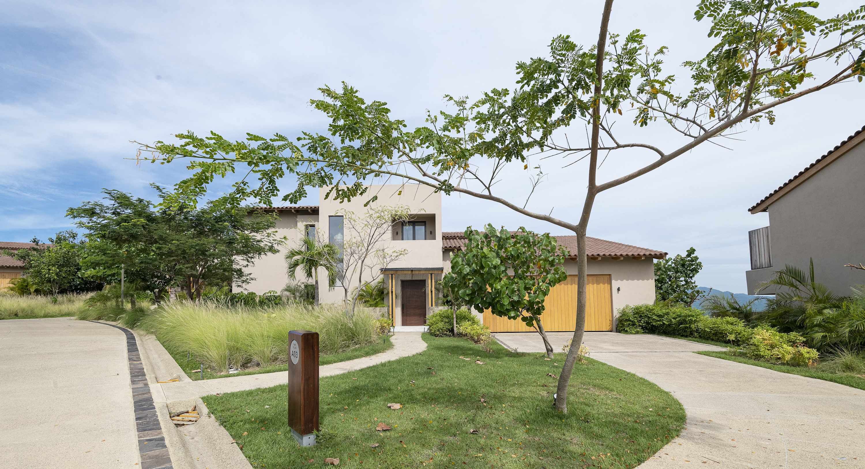 Uma área residencial com uma casa, um jardim frontal, uma entrada de carros e uma garagem.
