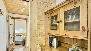 A wooden cabinet with glass doors, a kettle, and a cactus on a countertop.