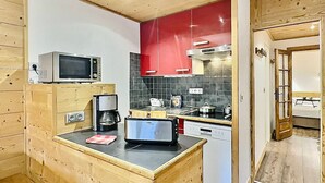 A compact kitchen with a microwave, coffee maker, toaster, and a stove.