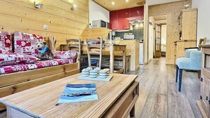 A cozy room with a wooden sofa, a dining table, and a kitchen area.