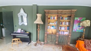A living room with a piano, a bookshelf, a lamp, and a painting. - Grande Attico by PortofinoVacanze (Rapallo)