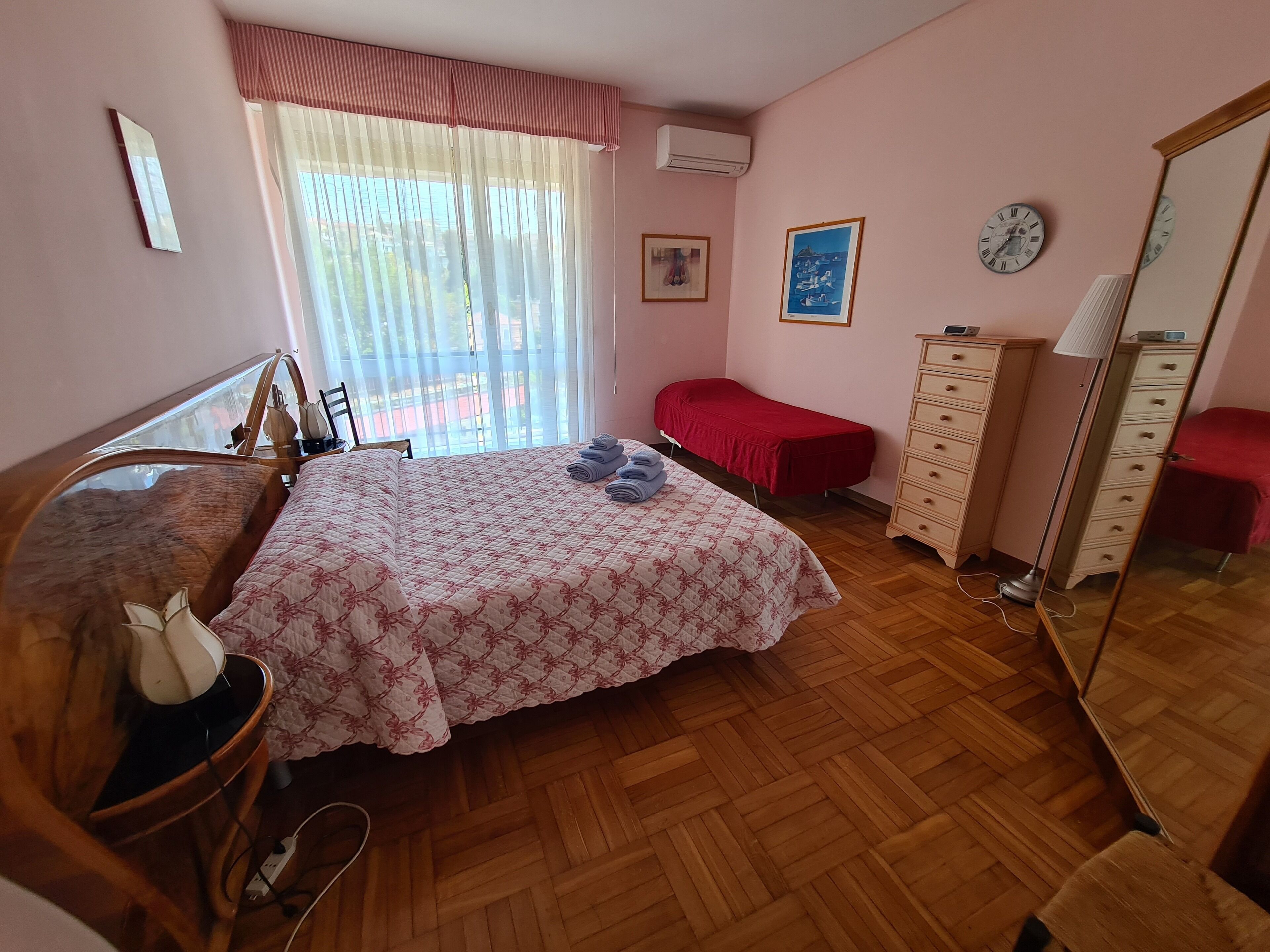 Un dormitorio con cama, mesita de noche, cómoda y espejo.