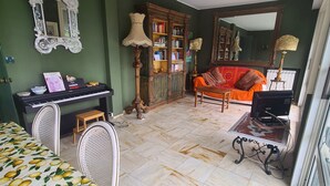 A room with a piano, a bookshelf, a sofa, and a bed with a lemon pattern bedspread. - Grande Attico by PortofinoVacanze (Rapallo)