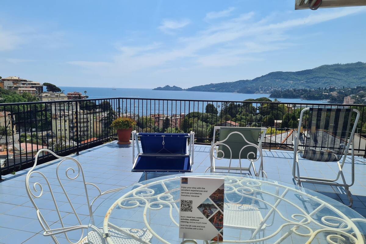 A balcony with a table, chairs, and a sign about booking a boat tour.