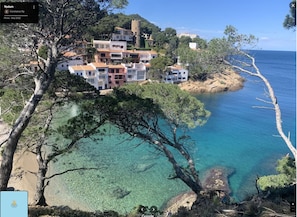A coastal town with buildings on a hillside overlooking clear blue waters.