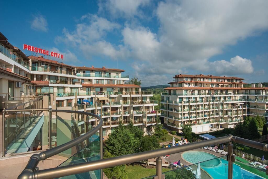 Een hotel met meerdere verdiepingen, balkons, een zwembad en een heldere lucht.