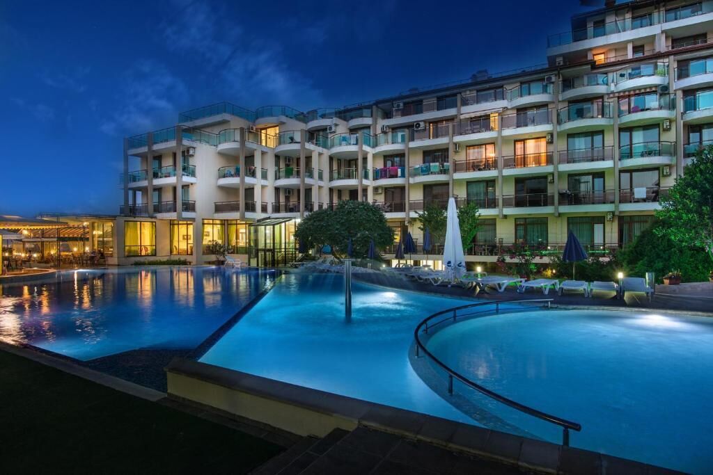 A multi-story hotel with a swimming pool, balconies, and outdoor seating areas.