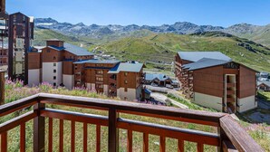 A mountain resort with wooden buildings, a balcony, and a view of the mountains. - Renovated 2-bedroom apartment in Val Thorens with WiFi (Val Thorens)