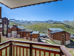 A mountain resort with wooden buildings, a balcony, and a view of the mountains.