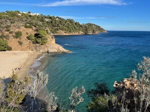 Eine Küstenlandschaft mit Sandstrand, klarem, blauem Meer und felsigen Klippen.