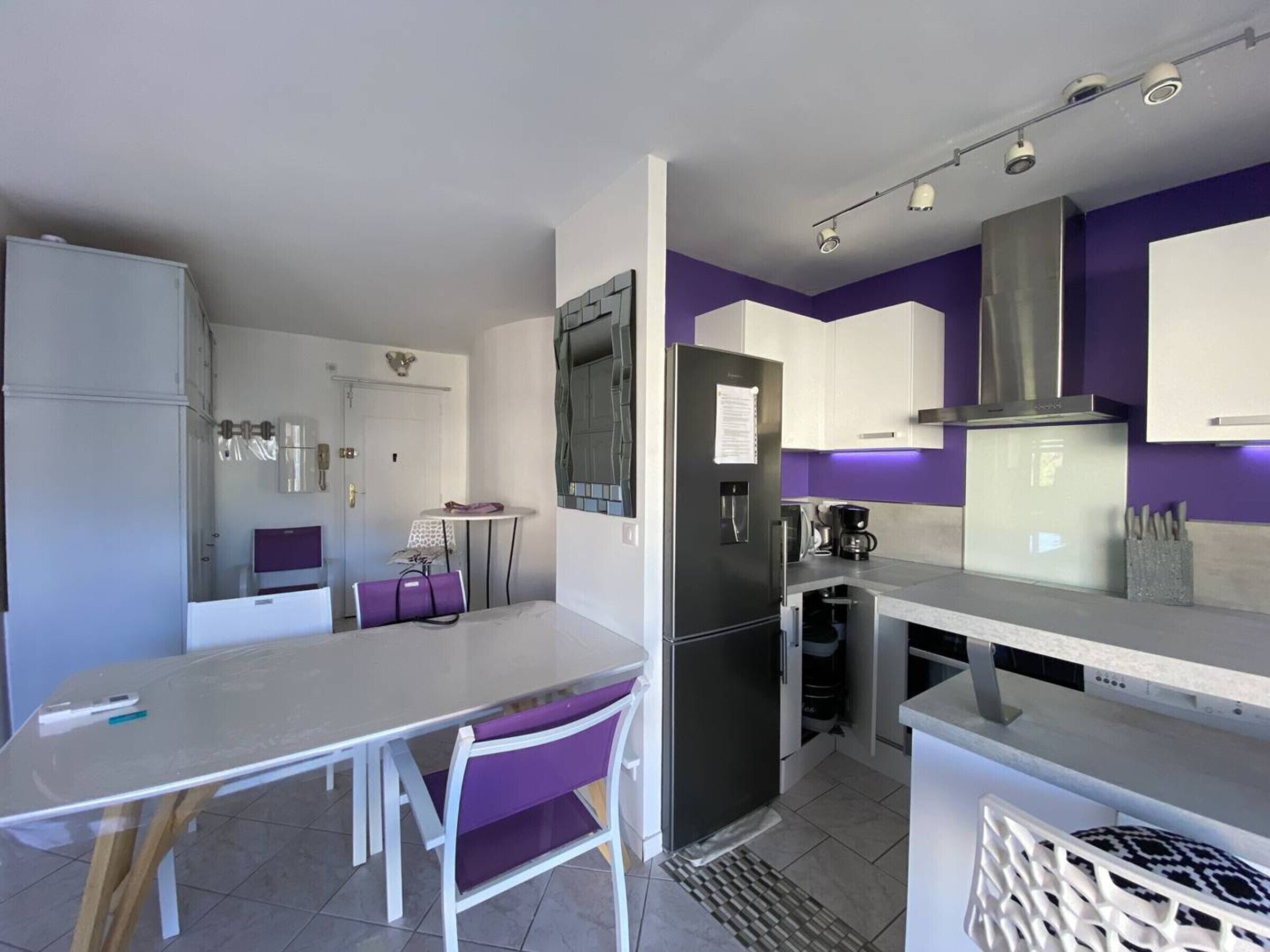 A compact kitchen with a refrigerator, stove, and a dining area with a table and chairs.