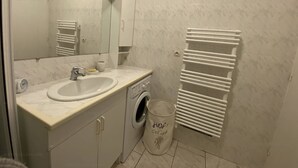A bathroom with a sink, mirror, towel rack, and a washing machine. - Modern T3 in Central Cavalaire - Walk to Beach & Shops, Parking, A/C, Spacious Terrace (Cavalaire-sur-Mer)