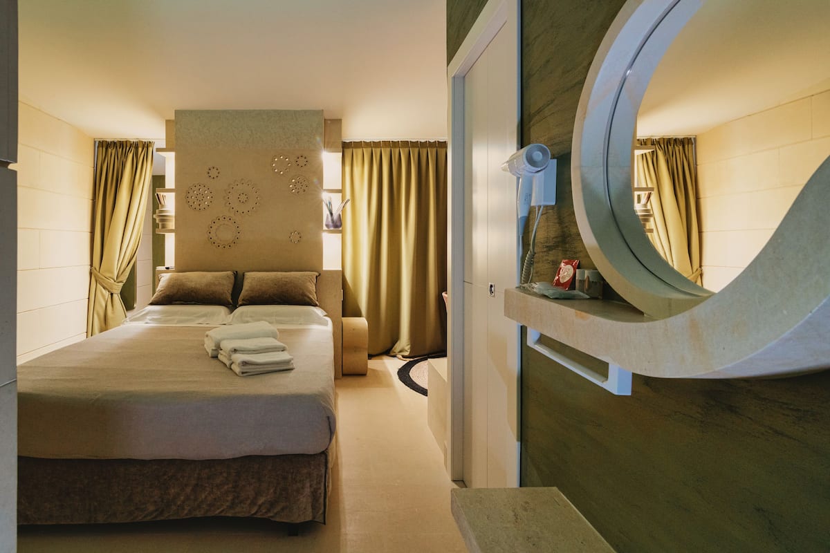 Ein Hotelzimmer mit einem Bett, einem runden Spiegel und einem an der Wand befestigten Fön.