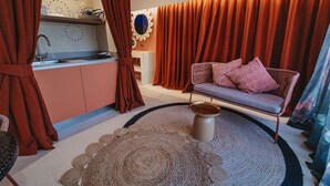 A modern living room with a sofa, a coffee table, and a kitchen area with a sink and cabinets.
