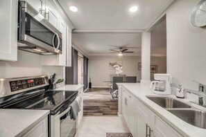 A modern kitchen with a microwave, stove, and sink. - GP46A | G. Prairie Haven | 2BD | Pool | Patio (Grand Prairie)