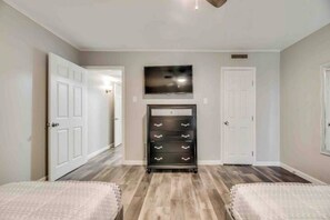 A bedroom with a bed, a dresser, a television, and a door.