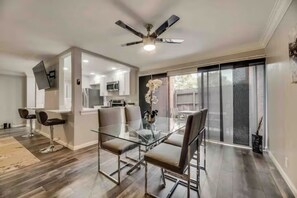 A modern kitchen with a dining area, a ceiling fan, and a sliding glass door leading to a patio.