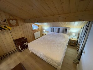 A wooden-paneled bedroom with a bed, bedside lamps, and a window. - Cozy 2BR Apt at Les Saisies, Close to Slopes, Sleeps 6, South Balcony, Garage Included (Les Saisies)