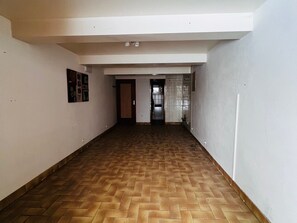 A hallway with a herringbone-patterned wooden floor, white walls, and a door leading to another room. - Cozy 2BR Apt at Les Saisies, Close to Slopes, Sleeps 6, South Balcony, Garage Included (Les Saisies)